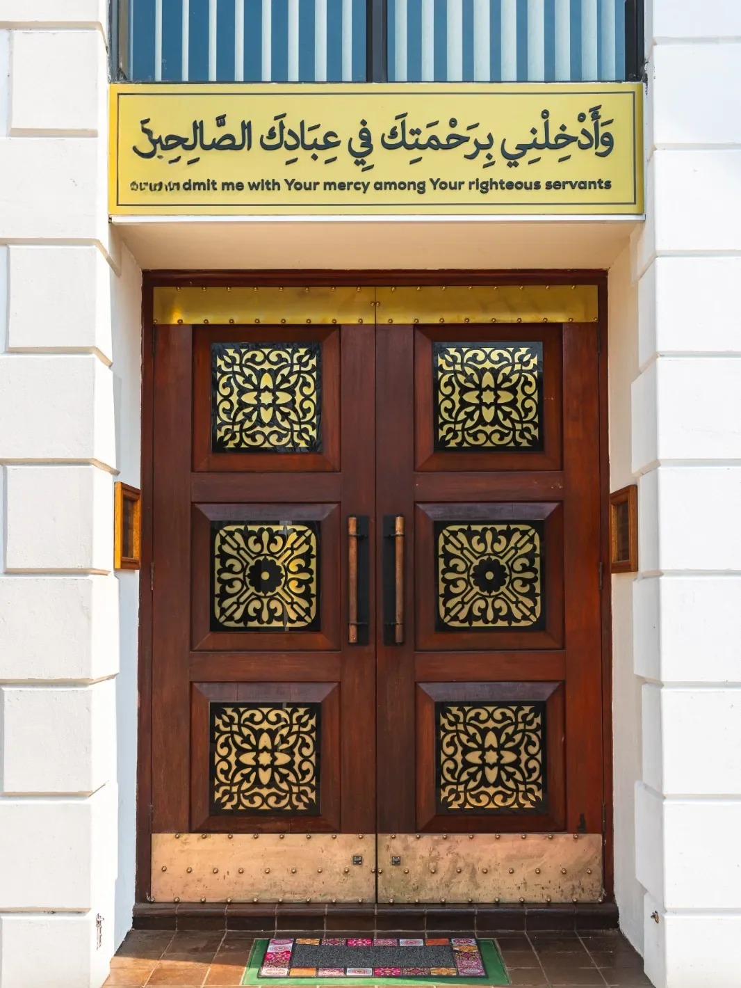 Main entrance doors beneath a dua inscription